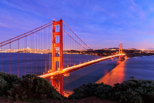 Car lights blur over Golden Gate Bridge with San Francisco lit at night. High quality photo