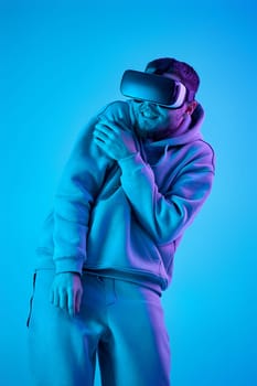 man using virtual reality glasses and playing video games on blue background. Neon lighting