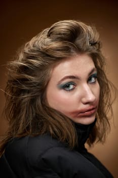 portrait of woman with smudged lipstick and stylish hairstyle in black jacket on beige background.