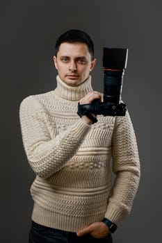 Professional caucasian photographer in sweater with digital camera on gray background