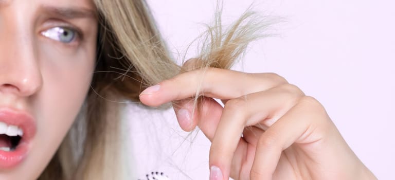 Closeup alluring portrait of beauty cosmetic clean skin woman having brittle dry hair problem. Grimacing frustrated sad facial expression in pink isolated background. Damaged and hair loss concept.