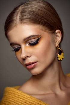 Beauty blonde model girl with fashionable creative make-up, bright eye line. Creative yellow eye makeup ideas.