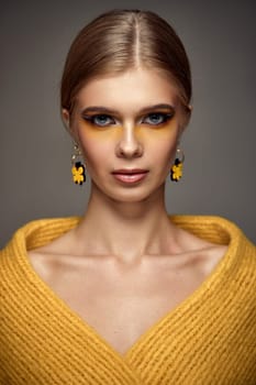 magnificent beauty blonde model woman with fashionable creative make-up and yellow earrings. Creative eye makeup ideas. autumn make-up