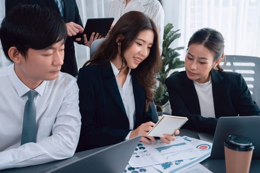 Harmony in office concept as business people analyzing dashboard paper together in workplace. Young colleagues give ideas at manager desk for discussion or strategy planning about project.