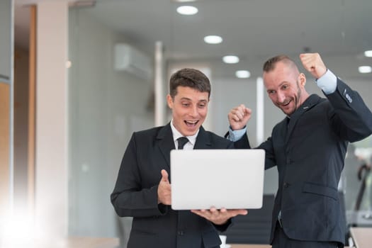 Two business people talk project strategy at office meeting room. Businessman discuss project planning with colleague at modern workplace while having conversation and advice on financial data report...