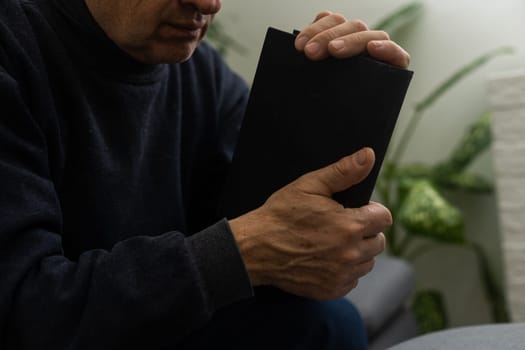 Senior man praying, holding Bible.