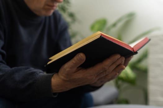 Senior man praying, holding Bible.