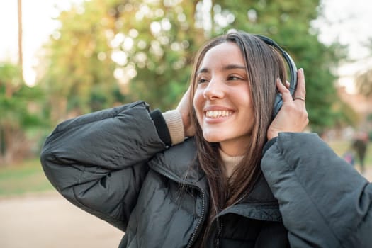 Happy woman using headphones enjoying music, podcast our audio books outdoors in the park. High quality photo