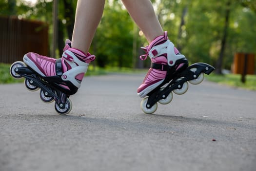 A woman rollerblading on an asphalt alley. A city park suitable for sports. Playing sports outdoors. Active relaxation in nature.