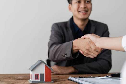 Real estate agent or realtor shakes hands with her client after making the deal in the office. cropped shot..