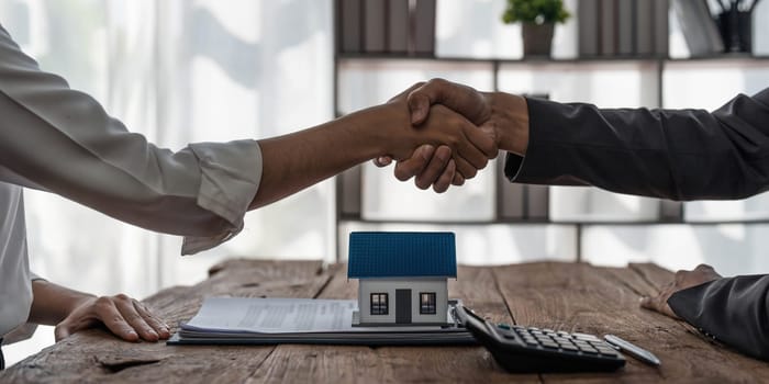 Real estate agent or realtor shakes hands with her client after making the deal in the office. cropped shot..