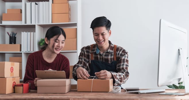 Young asian people couple Male and female small business owner checking online orders and packing the product together