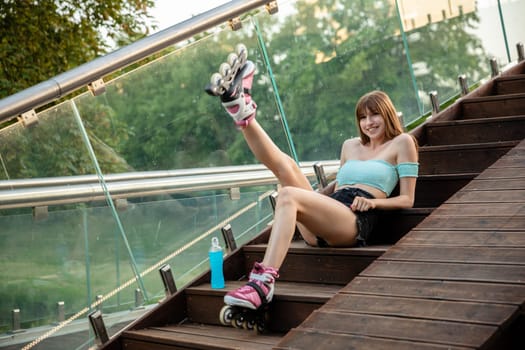 A young girl stretches her muscles after a workout. A teenage girl on roller skates relaxes while sitting on a wooden staircase. Smiling girl lifts straight leg up.
