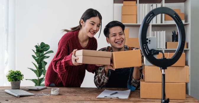 Young asian people couple Male and female small business owner checking online orders and packing the product together