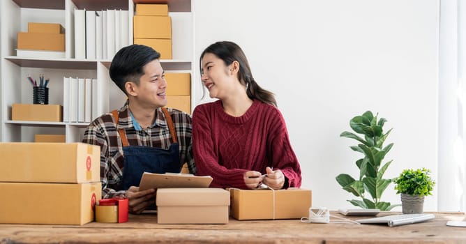 Young asian people couple Male and female small business owner checking online orders and packing the product together