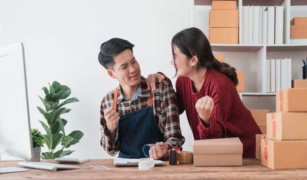 Young asian people couple Male and female small business owner checking online orders and packing the product together