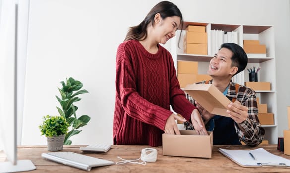 Young asian people couple Male and female small business owner checking online orders and packing the product together