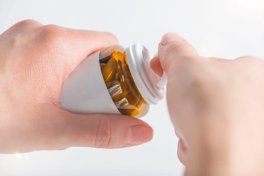 Antidepressants, taking pills for depression and disorders of the central nervous system. A woman's hand opens a bottle of antidepressants close-up on a white background
