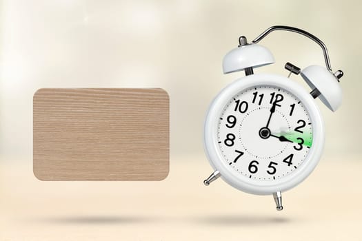 Change time. Summer time concept, on a wooden background. A white alarm clock with a minute hand indicates that the time has been moved forward an hour with copy space