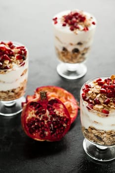 Healthy delicious muesli with oatmeal and pomegranate on dark wooden background
