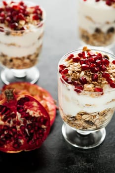 Fresh healthy home-made desset with muesli and pomegranate on dark wooden background