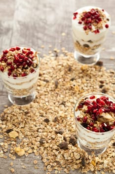 Muesli with oatmeal and pomegranate on top on wooden background