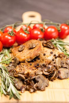 Close up viewon grilled pork and mushrooms next to cherry tomatoes