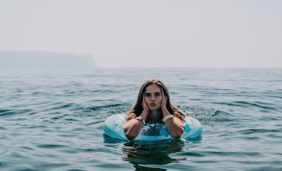 Woman summer sea. Happy woman swimming with inflatable donut on the beach in summer sunny day, surrounded by volcanic mountains. Summer vacation concept