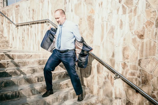 Portrait of a senior professional man in a suit with various problems. A middle-aged businessman with a briefcase descends the stairs.