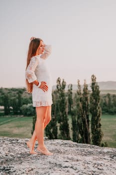 Romantic beautiful bride in white dress posing with sea and mountains in background. Stylish bride standing back on beautiful landscape of sea and mountains on sunset