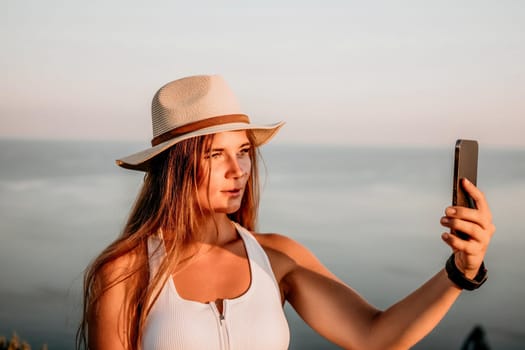 Woman travel sea. Happy tourist in hat enjoy taking picture outdoors for memories. Woman traveler posing on the beach at sea surrounded by volcanic mountains, sharing travel adventure journey