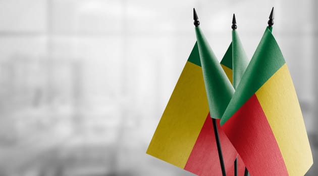 Small flags of the Benin on an abstract blurry background.