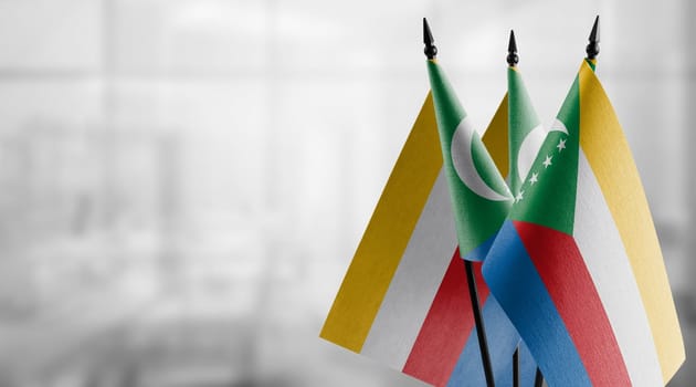 Small flags of the Comoros on an abstract blurry background.