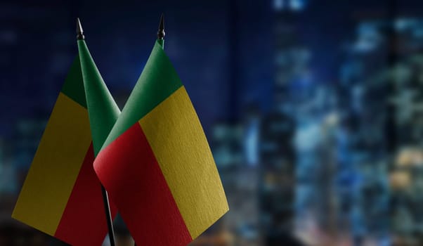 Small flags of the Benin on an abstract blurry background.