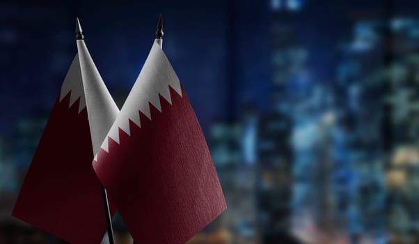 Small flags of the Qatar on an abstract blurry background.