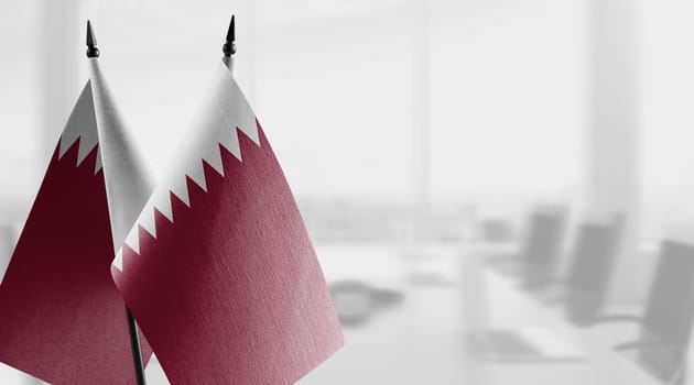 Small flags of the Qatar on an abstract blurry background.