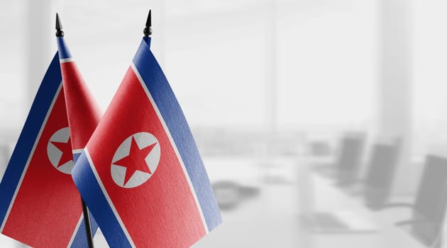 Small flags of the North Korea on an abstract blurry background.