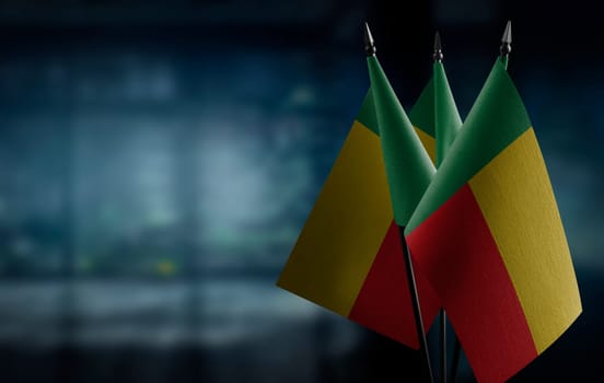 Small flags of the Benin on an abstract blurry background.