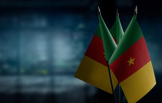 Small flags of the Cameroon on an abstract blurry background.