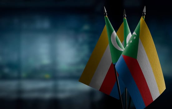 Small flags of the Comoros on an abstract blurry background.