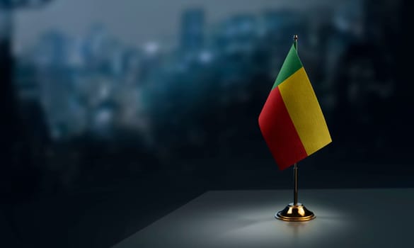 Small flags of the Benin on an abstract blurry background.