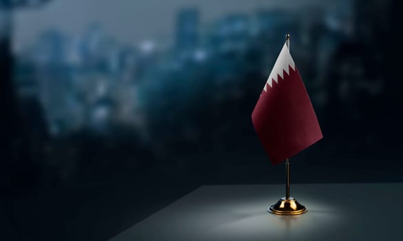 Small flags of the Qatar on an abstract blurry background.