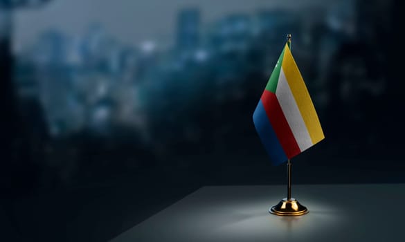 Small flags of the Comoros on an abstract blurry background.