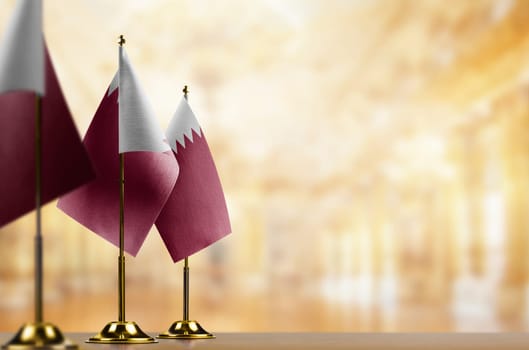 Small flags of the Qatar on an abstract blurry background.