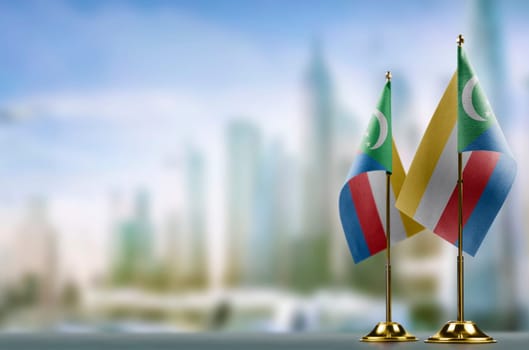 Small flags of the Comoros on an abstract blurry background.