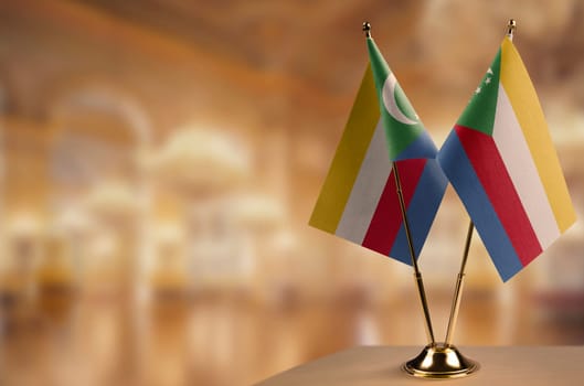 Small flags of the Comoros on an abstract blurry background.