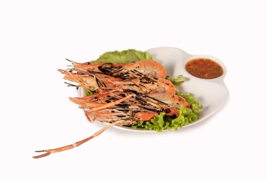 grilled shrimp on a plate served with spicy sauce over white background