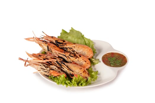 grilled shrimp on a plate served with spicy sauce over white background