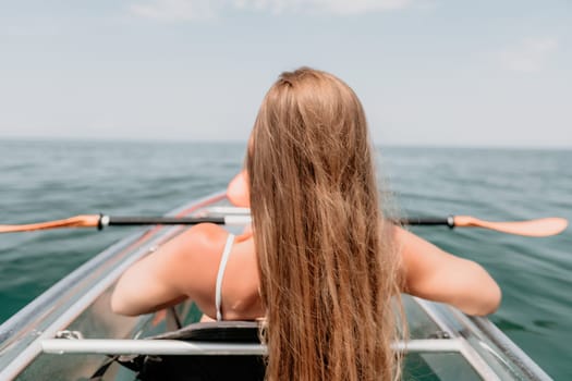 Woman in kayak back view. Happy young woman with long hair floating in transparent kayak on the crystal clear sea. Summer holiday vacation and cheerful female people having fun on the boat.