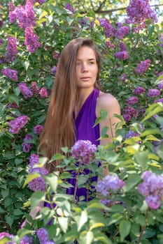 portrait of young woman with long hair outdoors in blooming lilac garden.